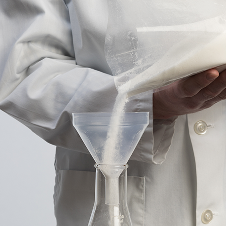 teflon bag with holding white powder being poured into a plastic labware funnel